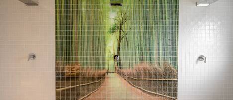 A bathroom with a large mural of a forest path, tiled walls, and a shower area.