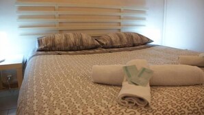 A neatly made bed with patterned bedding, a pillow, and rolled towels. - B&B Minicurcu (Acireale)