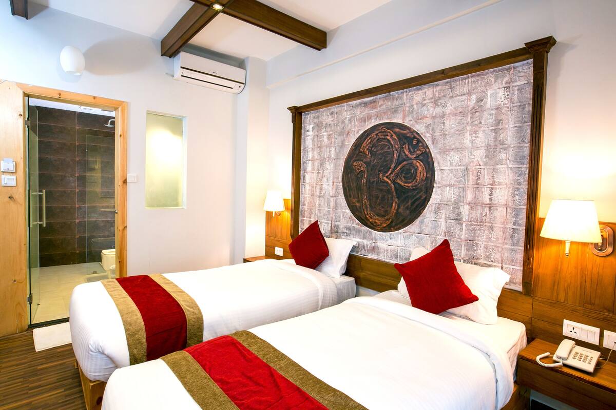 A hotel room with two beds, a large abstract artwork on the wall, and a wooden headboard.