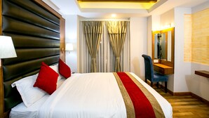 A hotel room with a large bed, a desk, a chair, and a mirror. - Beautiful Kathmandu Hotel (Kathmandu)