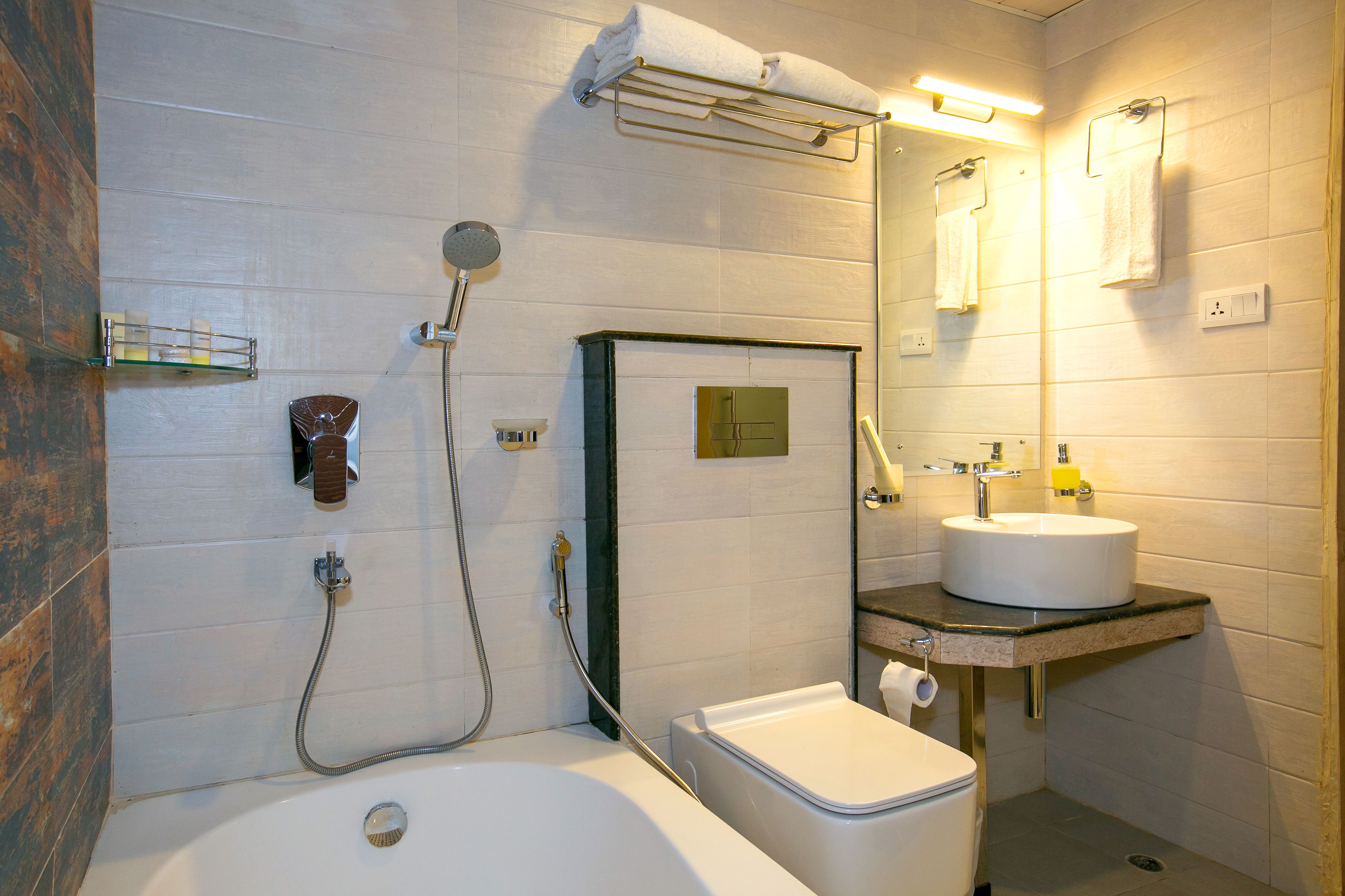 Et badeværelse med badekar, toilet og håndvask.