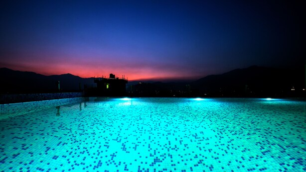 A swimming pool with a tiled floor and a view of mountains in the background. - Beautiful Kathmandu Hotel (Kathmandu)