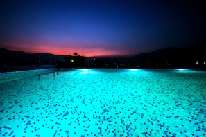 A swimming pool with a tiled floor and a view of mountains in the background. - Beautiful Kathmandu Hotel (Kathmandu)