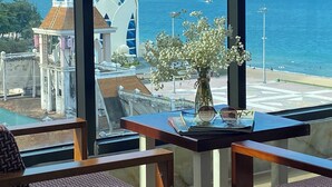 A view from a window overlooking a coastal area with a table featuring a vase of flowers and a pair of glasses. - Happy Light Central Nha Trang (Nha Trang)