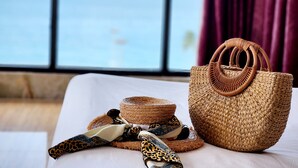 A bed with a woven basket and a leopard print scarf, a woven hat, and a woven handbag. - Happy Light Central Nha Trang (Nha Trang)