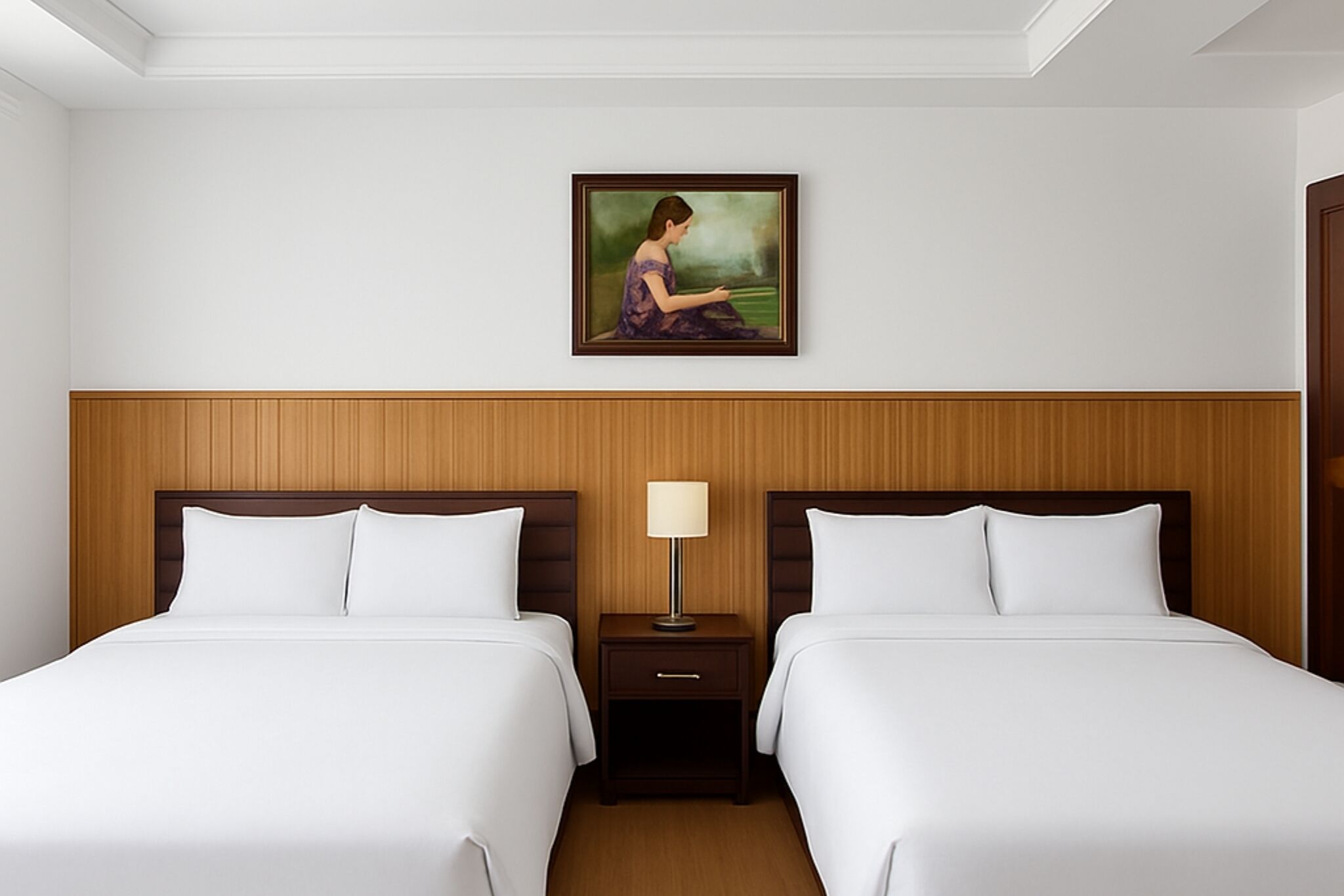 Quarto de hotel com duas camas, uma cabeceira de madeira, uma mesa de cabeceira com abajur e um quadro na parede.