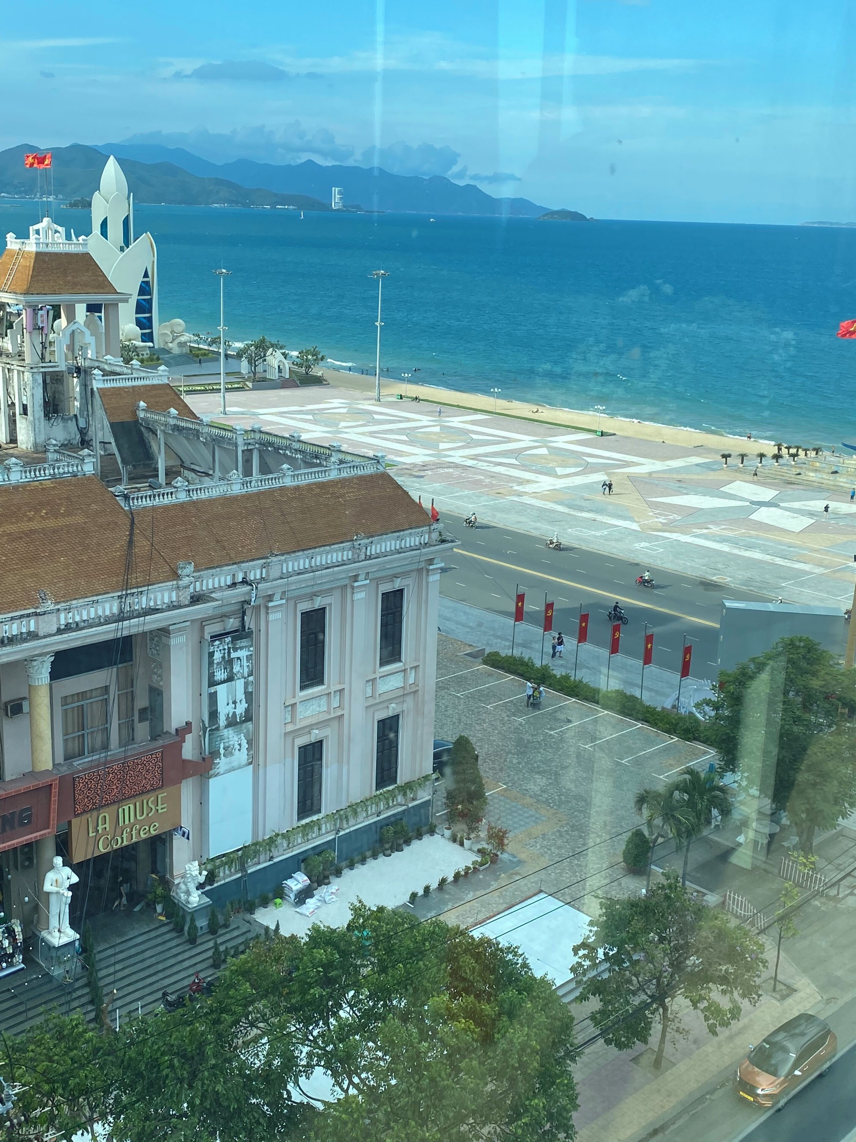 Un paisaje urbano costero con un edificio blanco destacado que tiene una cafetería en la planta baja.