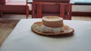 A wicker basket with a white object on a table, a checkered bench, and a view of the sea through a window. - Happy Light Central Nha Trang (Nha Trang)