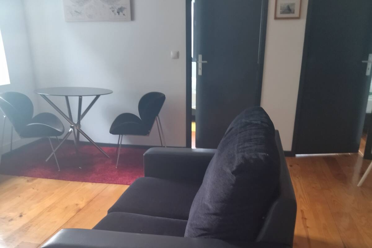 Un salon moderne avec un canapé foncé, une petite table ronde et deux chaises noires.
