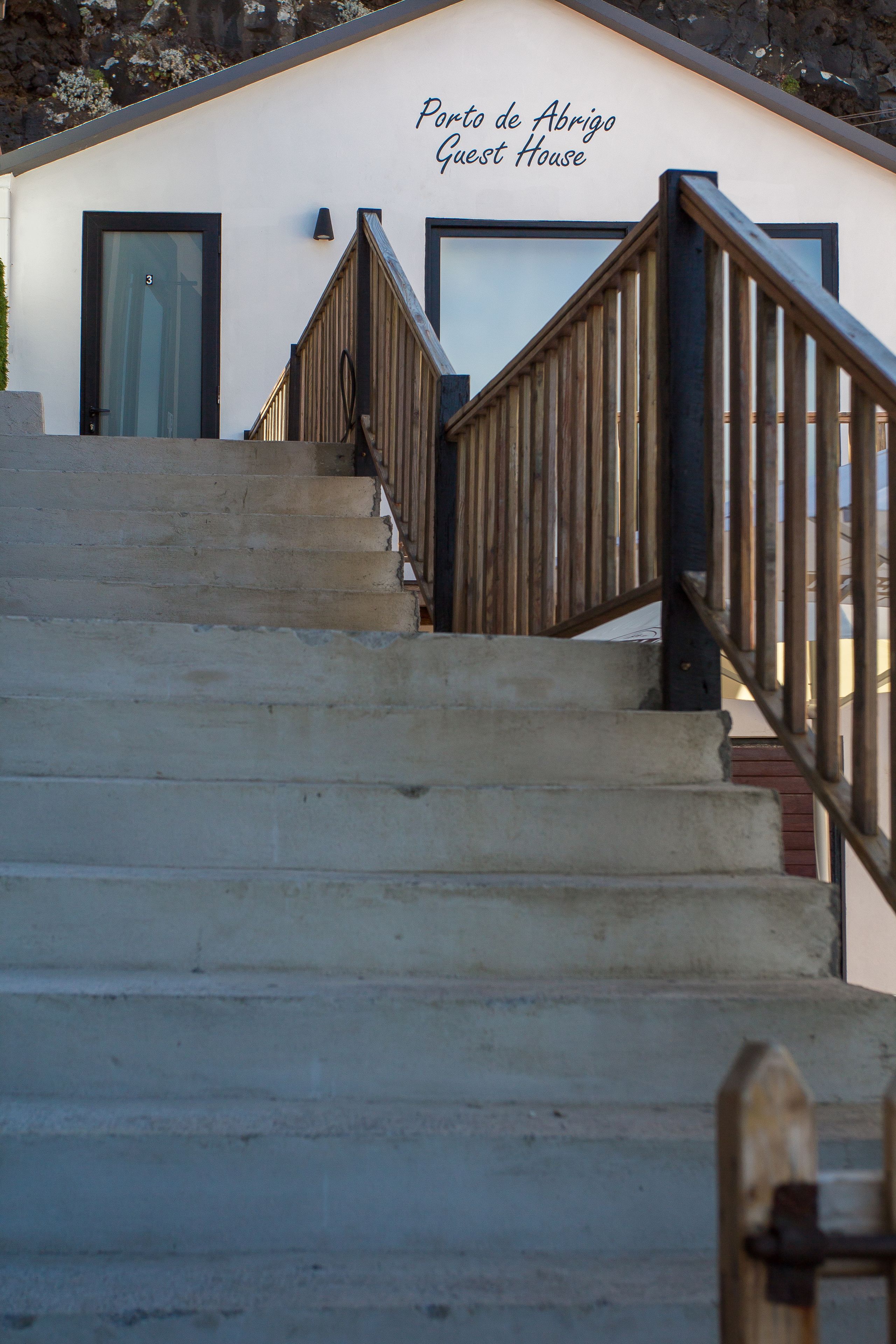 A staircase leading to a building labeled "Porto de Abrigo Guest House."