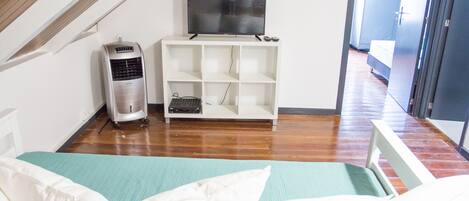 A room with a bed, a TV on a stand, and a heater.