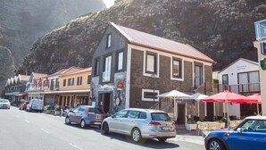 A street view with buildings, parked cars, and a mountainous backdrop.