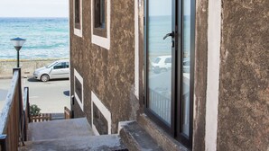 A building with a concrete exterior, a glass door, and a view of the ocean.