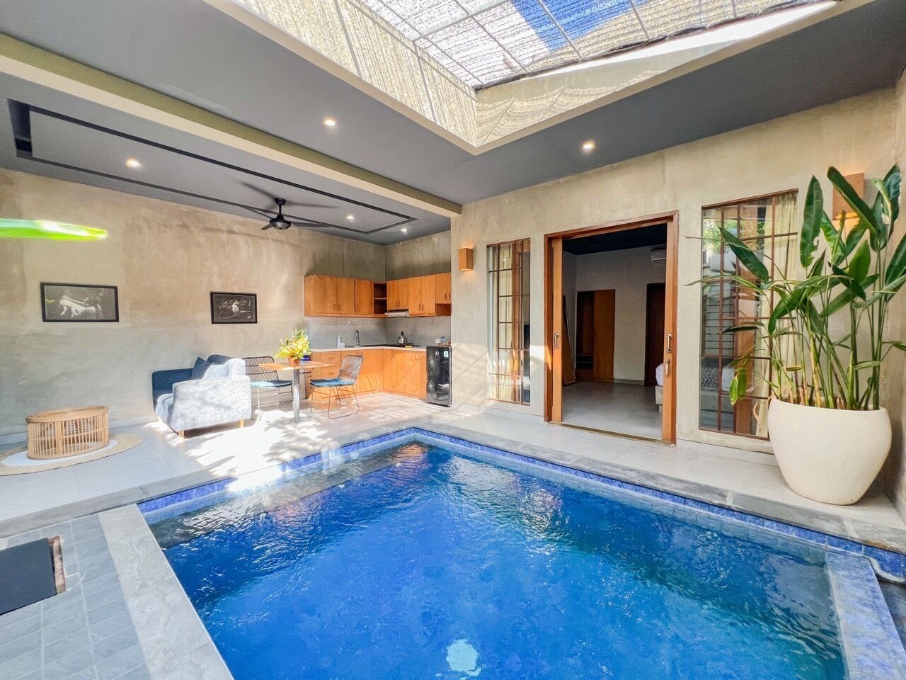 Un área de piscina interior moderna con tragaluces, una cocina y un comedor.