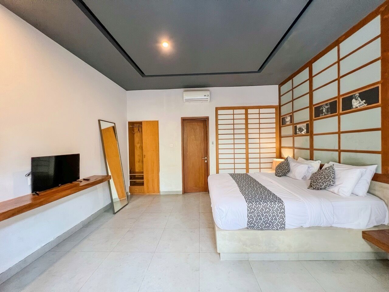 A bedroom with a bed, a TV, a wardrobe, and a sliding door.