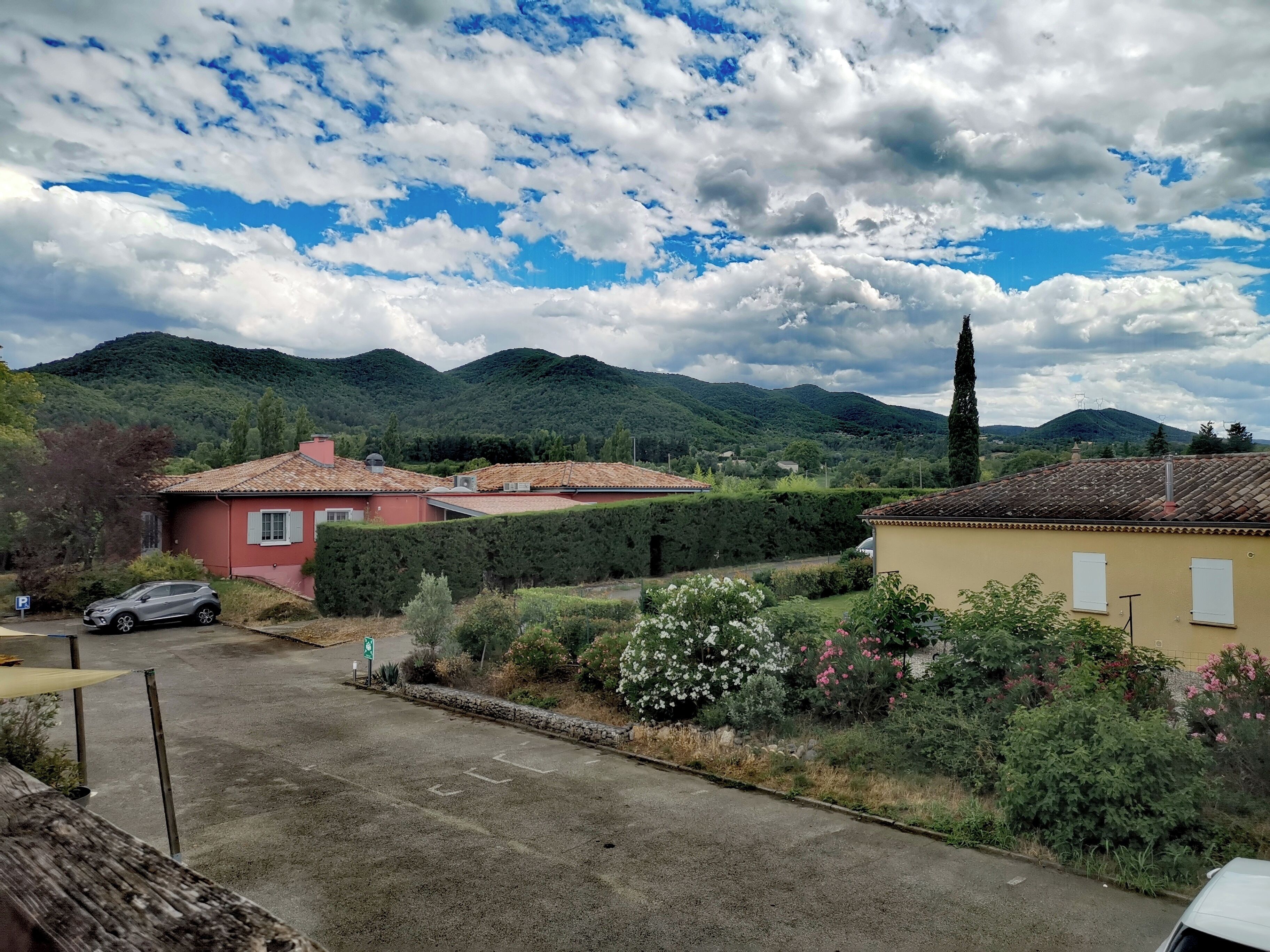 A residential area with houses, a paved road, and a mountainous backdrop.