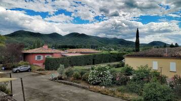 A residential area with houses, a paved road, and a mountainous backdrop.