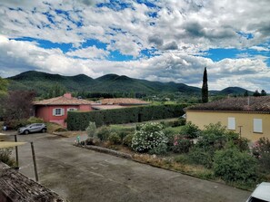 A residential area with houses, a paved road, and a mountainous backdrop. - Hotel Rose des vents (Baix)