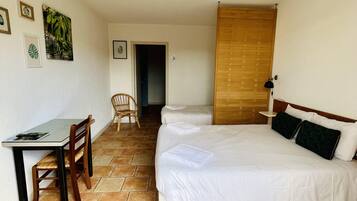 Une pièce avec un lit, un bureau et une chaise. Des tableaux encadrés ornent le mur.