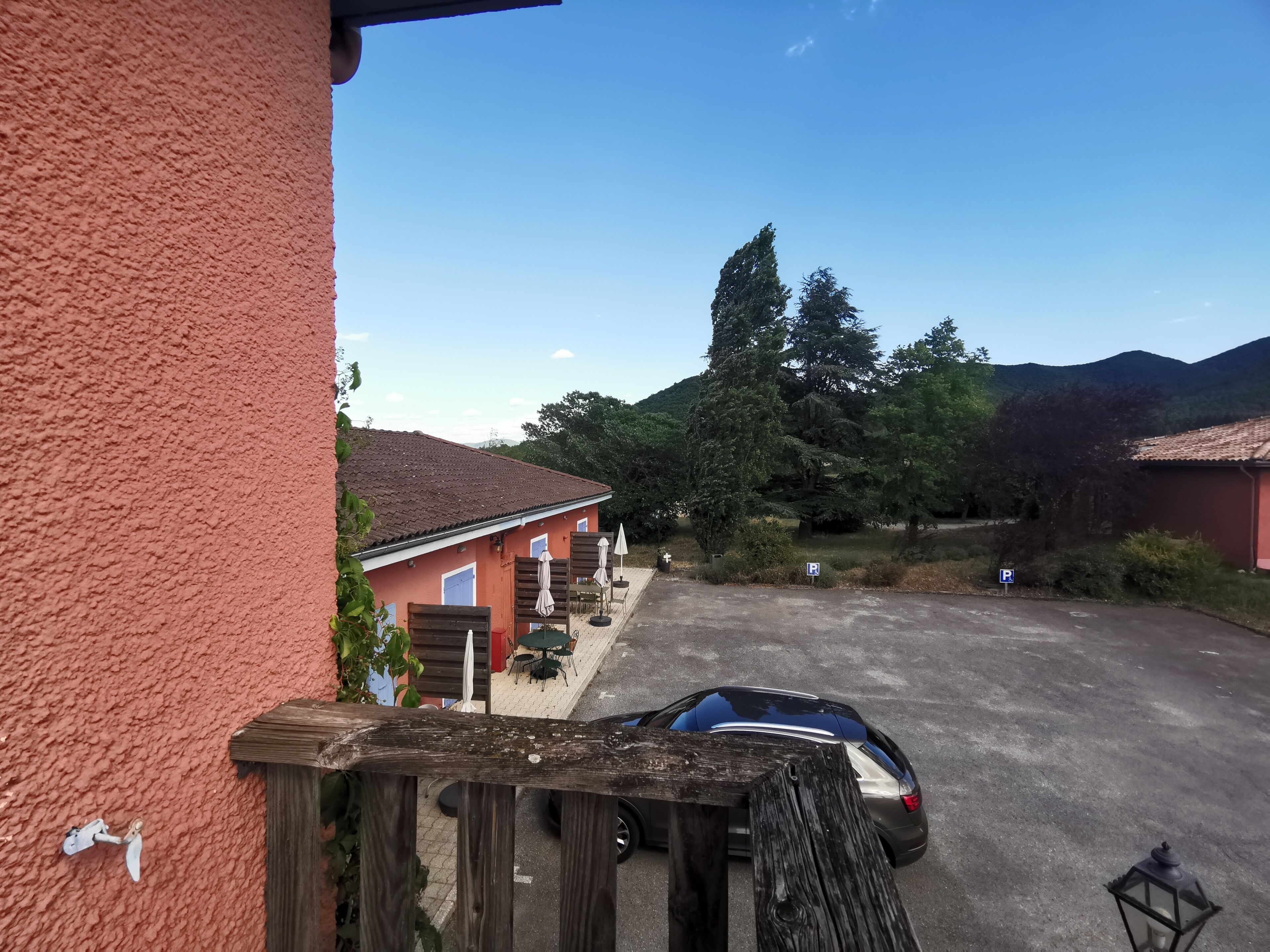 A residential area with a parked car, a wooden fence, and a building with a red exterior.