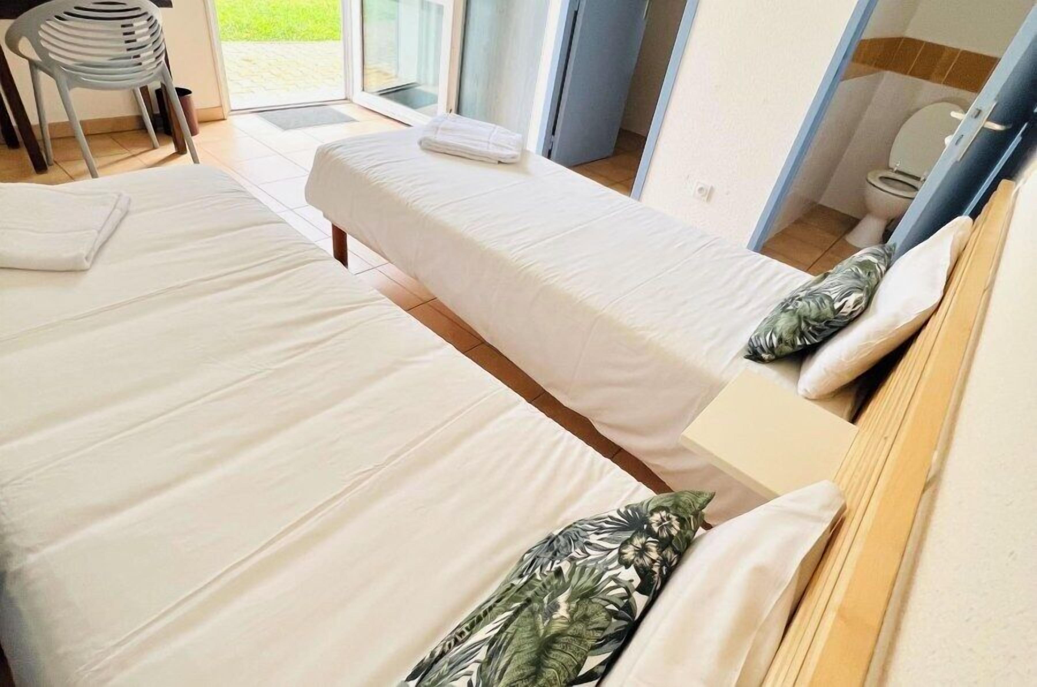 Een hotelkamer met twee bedden, een stoel en uitzicht op het landschap.