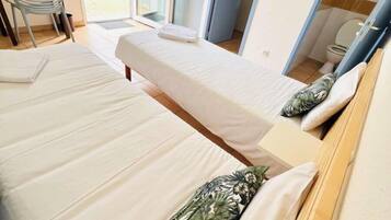 Een hotelkamer met twee bedden, een stoel en uitzicht op het landschap.
