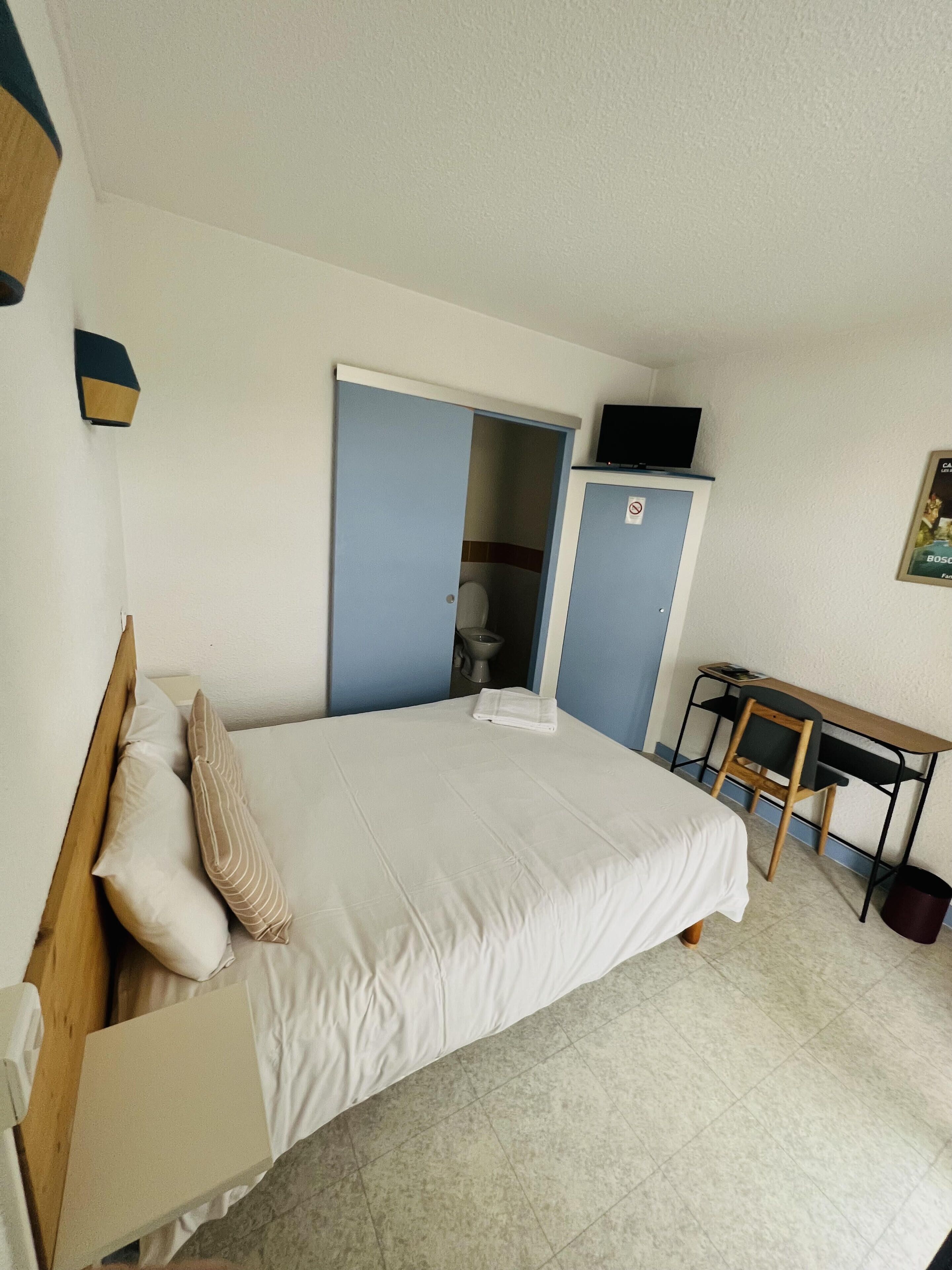 Une chambre à coucher avec un lit, un bureau et un téléviseur.