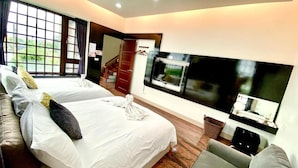 A hotel room with two beds, a sofa, a TV, and a window with a view of greenery. - Annabess (Wujie)