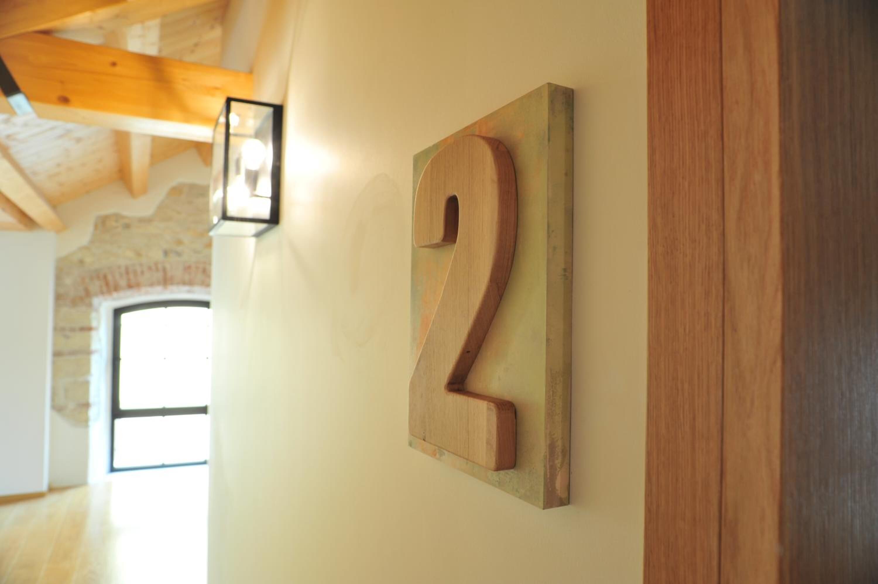 Un letrero de madera con el número 2 en una pared, una lámpara y una estructura de vigas de madera.