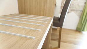 Une table de salle à manger en bois, ornée de plusieurs baguettes blanches, une chaise et un rideau vert en arrière-plan.