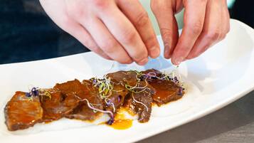 A person placing a garnish on a dish.