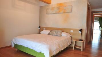 A bedroom with a large bed, bedside tables, a nightstand, and a painting on the wall.