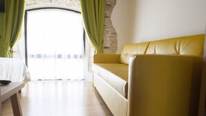 Une pièce avec un canapé jaune, une table en bois et une vue par la fenêtre, qui est ornée de rideaux verts.