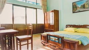 A bedroom with a wooden bed, a wooden chair, a wooden desk, and a large window. - Homestay Sunny's House (Ho Chi Minh City)