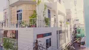 A multi-story residential building with balconies, potted plants, and visible electrical wiring. - Homestay Sunny's House (Ho Chi Minh City)