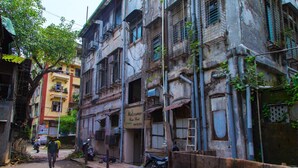 A narrow street with old buildings, a 'Welcome' sign, and a motorcycle parked on the side. - Hotel Tourister (Mumbai)