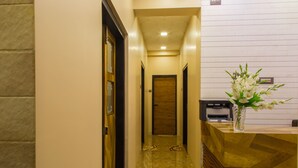 A hotel reception area with a marble floor, a reception desk, and a wooden door at the end of the hallway. - Hotel Tourister (Mumbai)