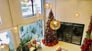 Eine großzügige Lobby mit einem großen Weihnachtsbaum, gemütlichen Sitzbereichen und moderner Pendelleuchten.