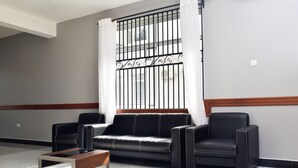 A modern living room with a black leather sofa, two armchairs, and a glass coffee table. - Sea Crest Hotel (Kiwengwa)