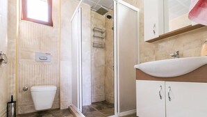Une salle de bain avec douche, toilettes et lavabo.