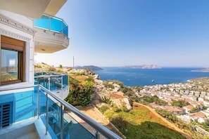 A modern building with a glass balcony overlooking a coastal town and the sea. - Kas Bakacak Begonvil Apart (Kas)