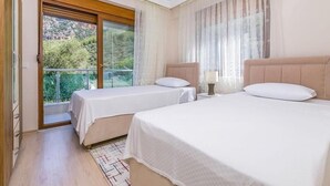 Une chambre d’hôtel avec deux lits, un balcon donnant sur un espace verdoyant et une porte-fenêtre coulissante.