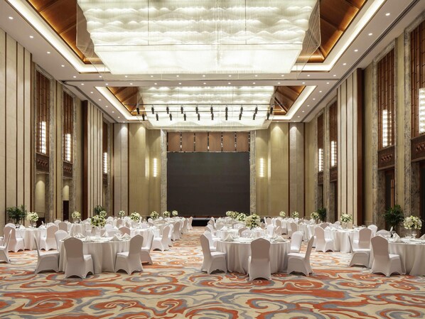 A banquet hall with round tables, white chairs, and a patterned carpet. - Pullman Changbaishan Resort (Baishan)