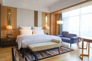Una habitación de hotel moderna con una cama grande, mesitas de noche, un escritorio y una silla.