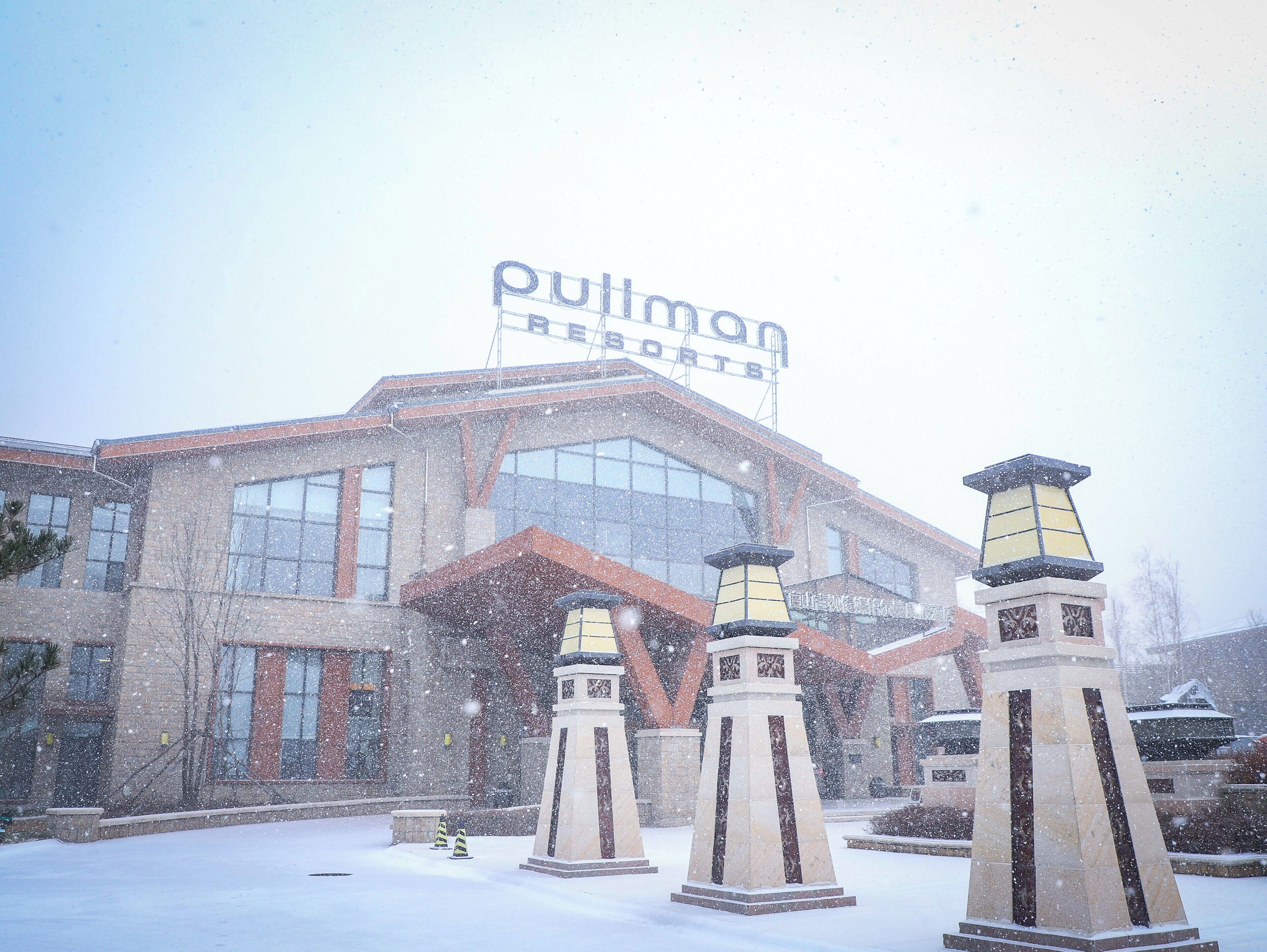 Un hotel con un cartel grande que dice "Pullman Resorts" y tres farolas al frente.