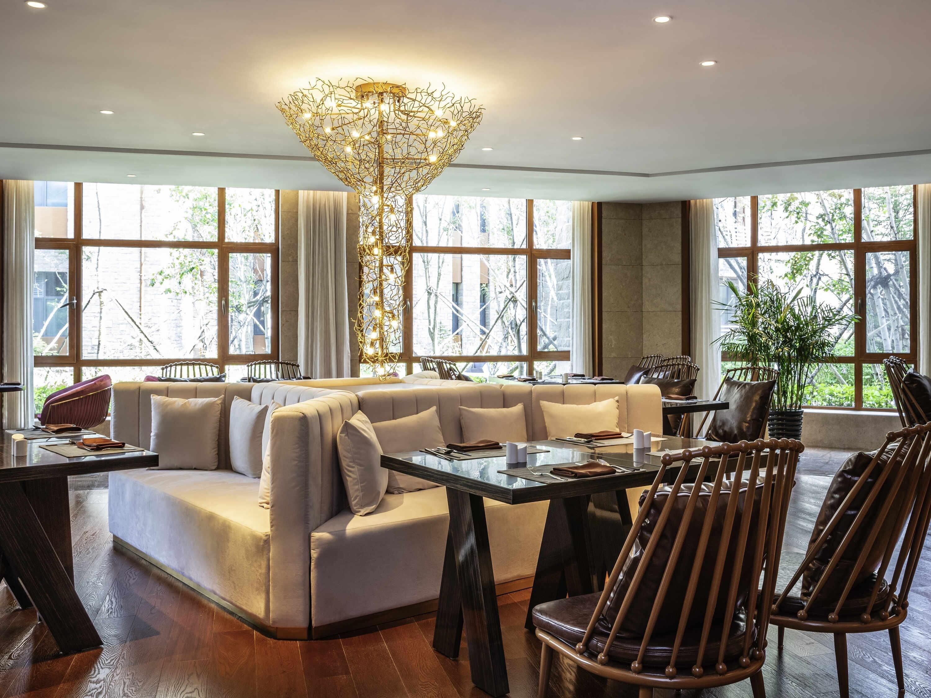 A modern lounge area with a sofa, dining table, chairs, and a unique chandelier.