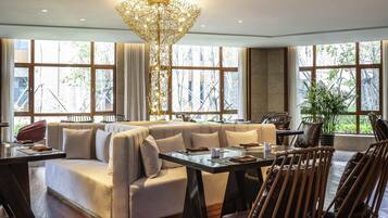 A modern lounge area with a sofa, dining table, chairs, and a unique chandelier.