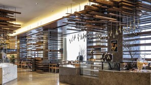 A modern interior with wooden slats on the ceiling, marble countertops, and a reception area with a glass display case. - Pullman Changbaishan Resort (Baishan)