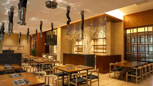 A restaurant with multiple tables and chairs, a bar area, and hanging light fixtures. - Pullman Changbaishan Resort (Baishan)