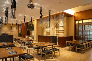 A restaurant with multiple tables and chairs, a bar area, and hanging light fixtures. - Pullman Changbaishan Resort (Baishan)